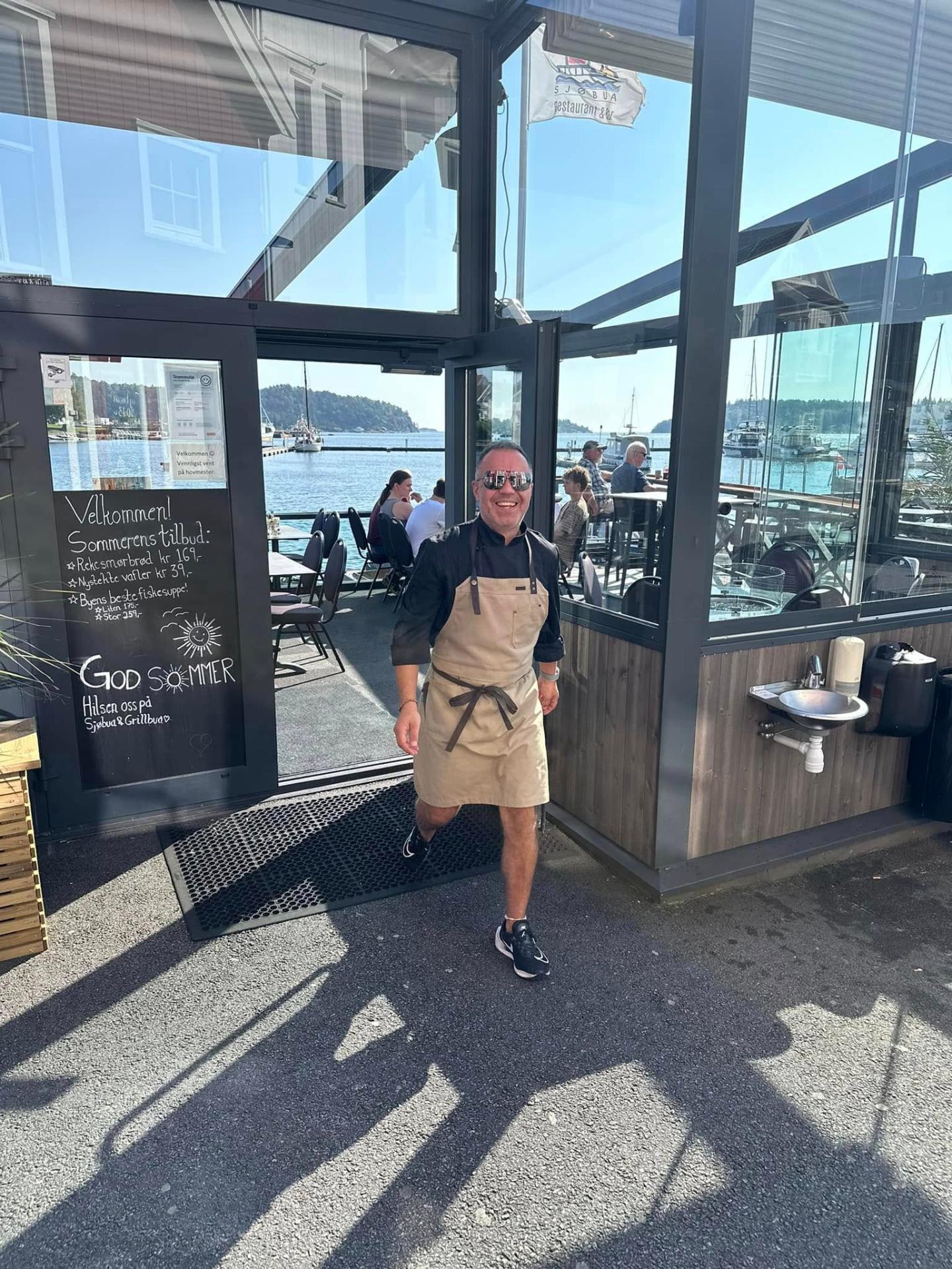 Kjøkkensjefen utenfor Sjøbua en sommerdag