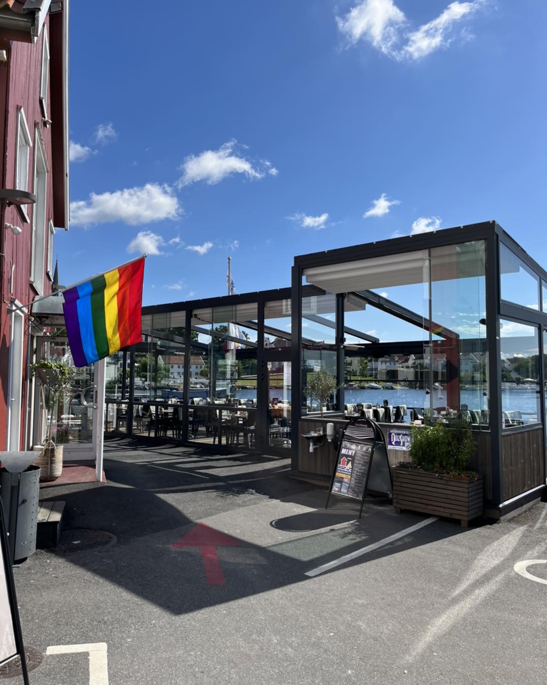 Inngangen til Sjøbua med pride-flagg og utsikt mot havna