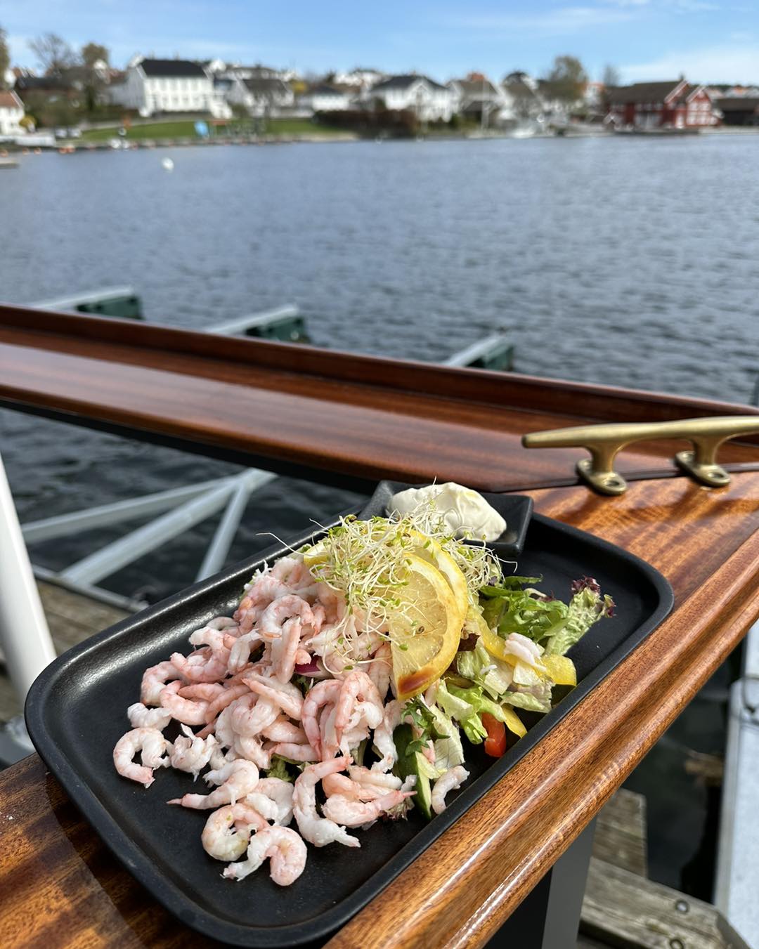 Rekefat med sitron og salat servert ved bryggekanten